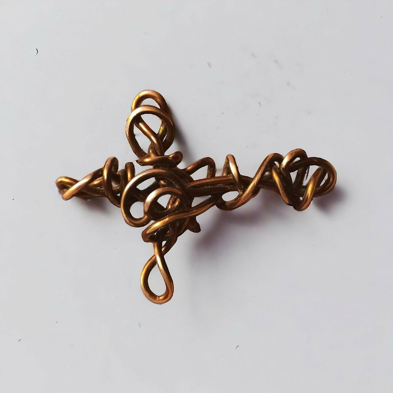 Artystyczny wisiorek przedstawiający krzyżyk z czystej miedzi, z unikalną, ażurową strukturą stworzoną metodą wire wrapping. Długość 6 cm.