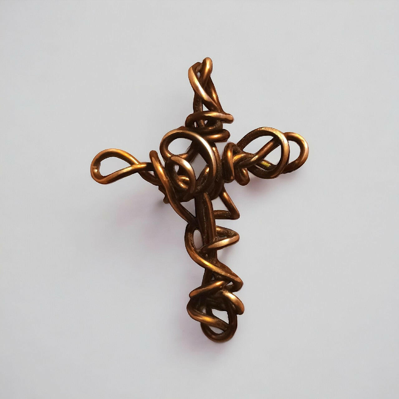 Miedziany wisiorek w kształcie krzyżyka, wykonany z czystej miedzi techniką wire wrapping. Długość około 6 cm.