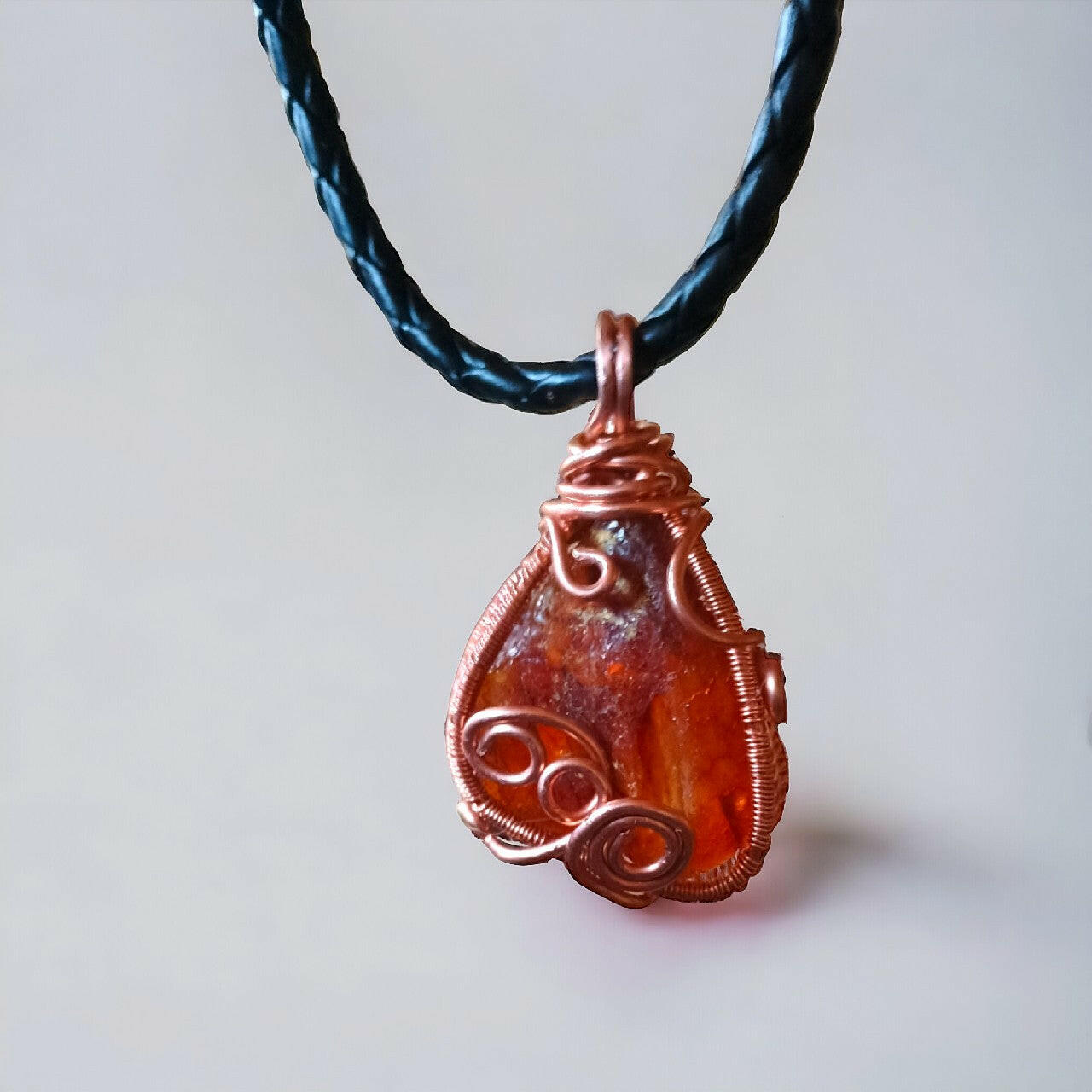 Artystyczny wisiorek z surowego, nieoszlifowanego bursztynu bałtyckiego, misternie oplecionego miedzianym drutem metodą wire wrapping. Bursztyn o unikalnym kształcie i inkluzjach. Całość zawieszona na trwałym, plecionym rzemieniu z bezpiecznym zapięciem magnetycznym. Długość 42 cm.