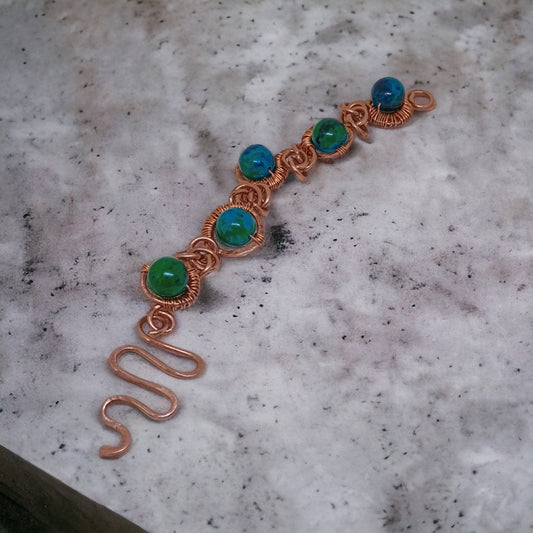 Precyzyjne owinięcie czystą miedzią podkreśla piękno i indywidualność każdego kamienia chryzokoli w tej wyjątkowej bransoletce