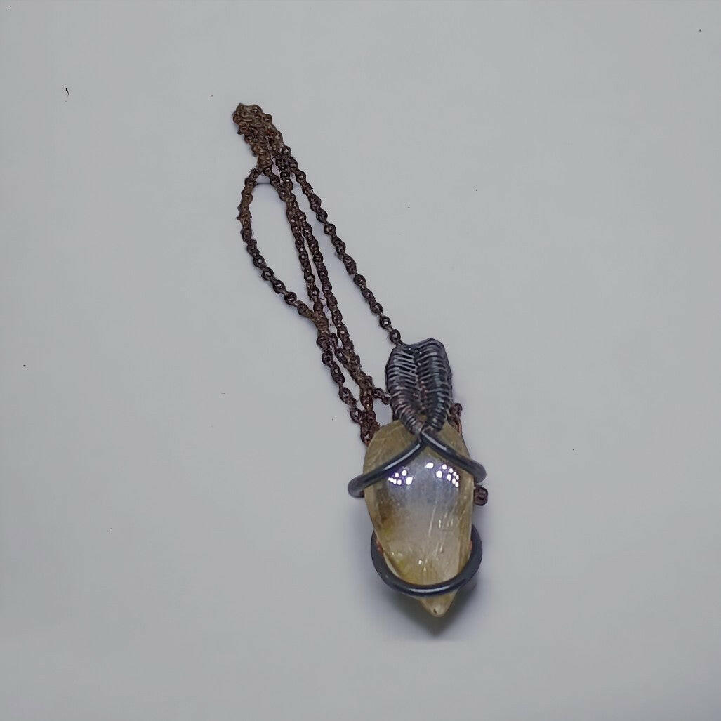 Ręcznie wykonany wisiorek z kwarcu rutylowego, opleciony czystą miedzią techniką wire wrapping. Miedź pokryta oksydą nadającą jej efekt patyny