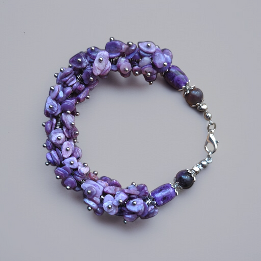 Bransoletka z małych kamieni Czaroitu splecionych w jedną całość wykończona dużymi elementami Czaroitu w owalnym kształcie i kulką z Czaroitu z metalowymi elementami i metalowym zapięciem