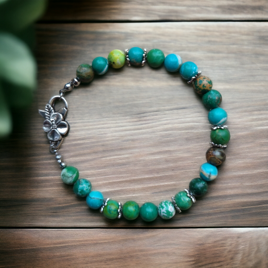 Ręcznie wykonana bransoletka z naturalnego jaspisu cesarskiego o unikalnym wzorze, z metalowymi elementami dekoracyjnymi. Zapięcie ozdobne, w formie kwiatka. Długość 21 cm z opcją bezpłatnej regulacji na życzenie klienta.