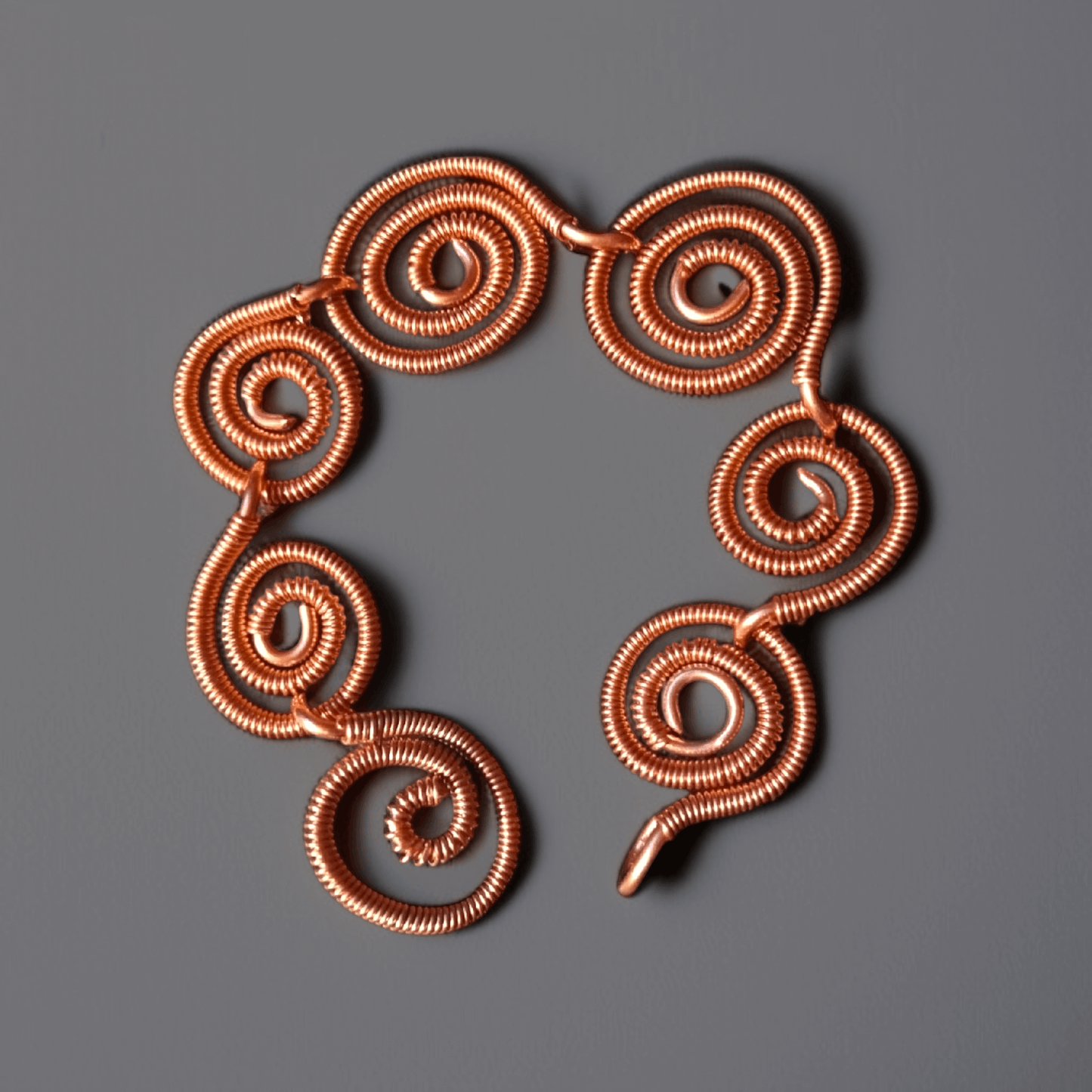 Bransoletka typu wire wrapping składająca się z połączonych ze sobą spiralnych okręgów dodatkowo owiniętych z czystej miedzi z zapięciem na haczyk
