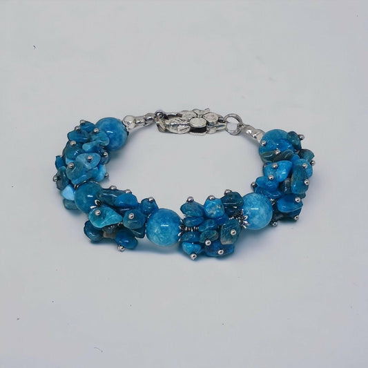 Wyrazista bransoletka handmade z nieregularnych bryłek apatytu w odcieniach błękitu, wzbogacona o delikatne, okrągłe koraliki chalcedonu. Kontrast faktur i odcieni tworzy dynamiczną i przyciągającą kompozycję