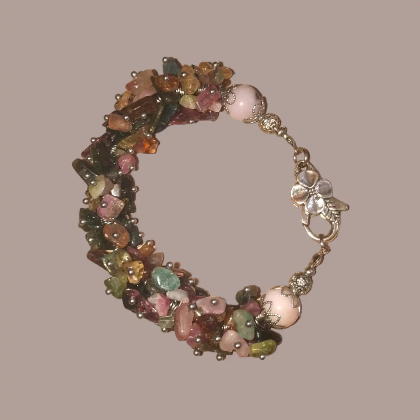 Bransoletka z małych wielokolorowych Turmalinów połączonych w większą całość z różowym opalem na końcu z ozdobnymi metalowymi elementami i dużym zapięciem metalowym w kształcie kwiatka